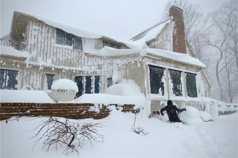Ein Anwohner entfernt Schnee von einem Gebäude in Amherst. Amerika friert zum Weihnachtsfest weiter bei Schneestürmen und frostiger Kälte.