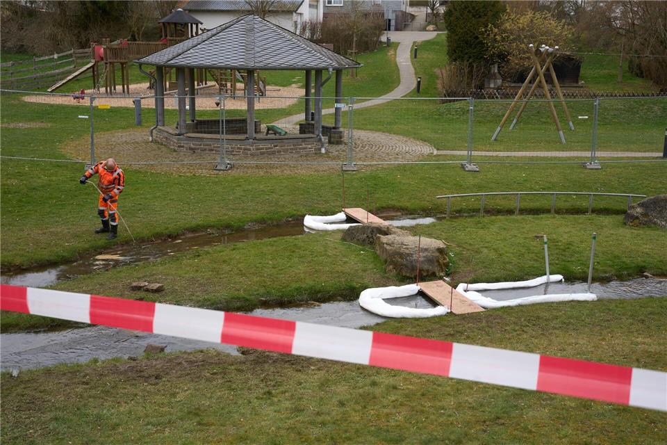 Ein Arbeiter pumpt mit Hilfe einer Ölsperre das durch Diesel verunreinigte Wasser aus dem Bach ab. Thomas Frey/dpa