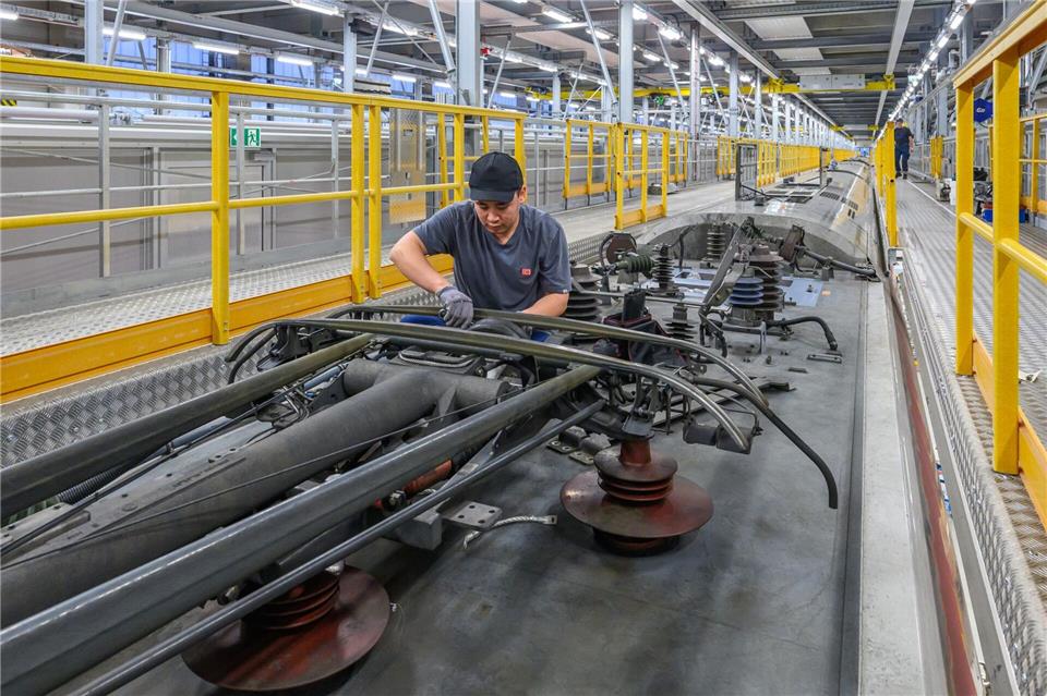 Ein Arbeiter repariert einen Stromabnehmer auf dem Dach eines ICE im ICE-4-Instandhaltungswerk der Deutschen Bahn. Das ICE-Werk in Cottbus wird am 11.01.2025 ein Jahr alt. Im ersten Jahr nach der Inbetriebnahme wurden hier insgesamt 13 ICE-4 Züge gewartet. Für 2025 sollen bereits doppelt soviel Züge gewartet werden. Zudem solle die sogenannte schwere Instandhaltung des ICE-4 schon jetzt vollständig in der Lausitz gebündelt werden, teilte die Deutsche Bahn mit.Patrick Pleul/dpa