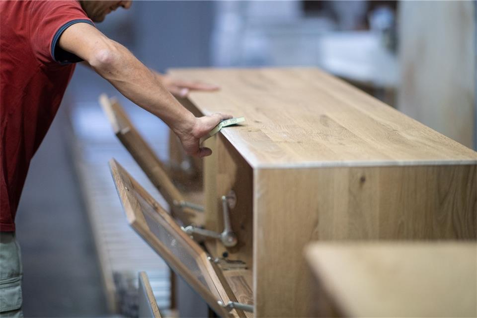 Ein Arbeiter schleift ein Möbelstück ab.