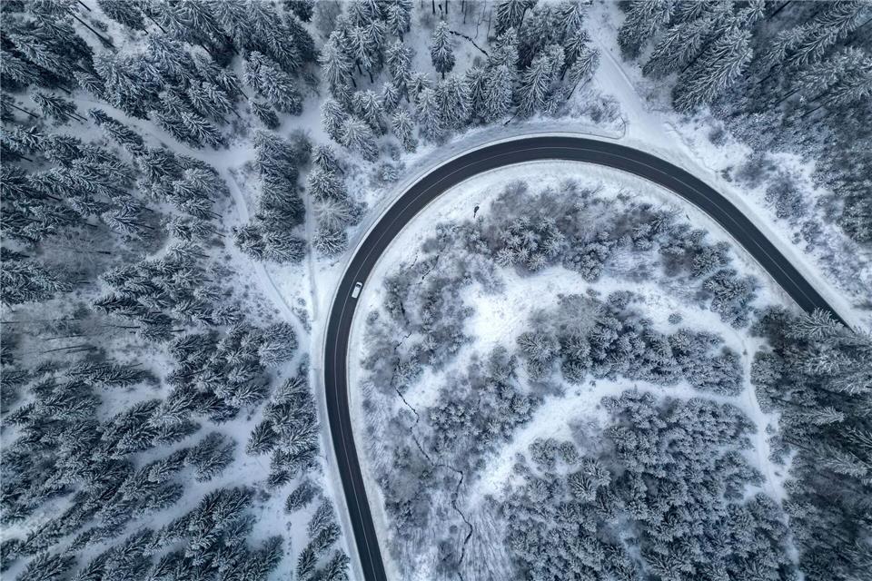 Ein Auto fährt auf einer Landstraße durch den winterlichen Wald im Vogtland.Jan Woitas/dpa