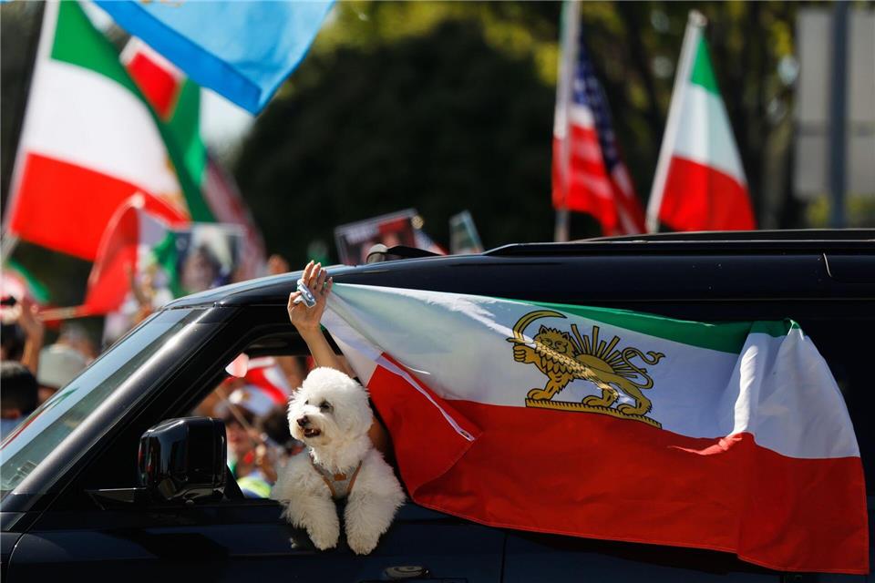 Ein Autofahrer befestigt eine iranische Flagge an einem Fenster.Caroline Brehman/AP/dpa