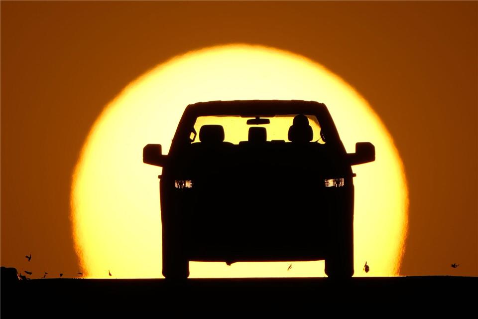 Ein Autofahrer wird von der untergehenden Sonne angestrahlt.Charlie Riedel/AP/dpa
