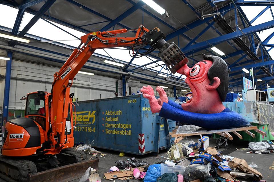 Ein Bagger hebt in Düsseldorf eine Pappfigur eines Rosenmontagszugs in den Müll. Nachdem die Motive zahlreiche Zuschauer begeisterten, werden sie abgerissen.Federico Gambarini/dpa