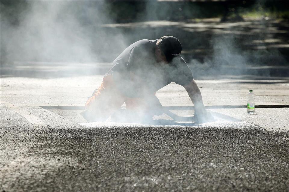 Ein Bauarbeiter repariert eine Straße in Berlin mit Bitumen, einem Bindemittel für Asphalt. (Symbolbild)Wolfgang Kumm/dpa