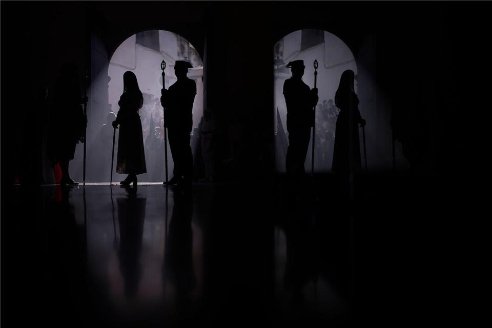 Ein Beamter der Guardia Civil (r) und ein Büßer nehmen an einer Prozession teil.Manu Fernandez/AP/dpa