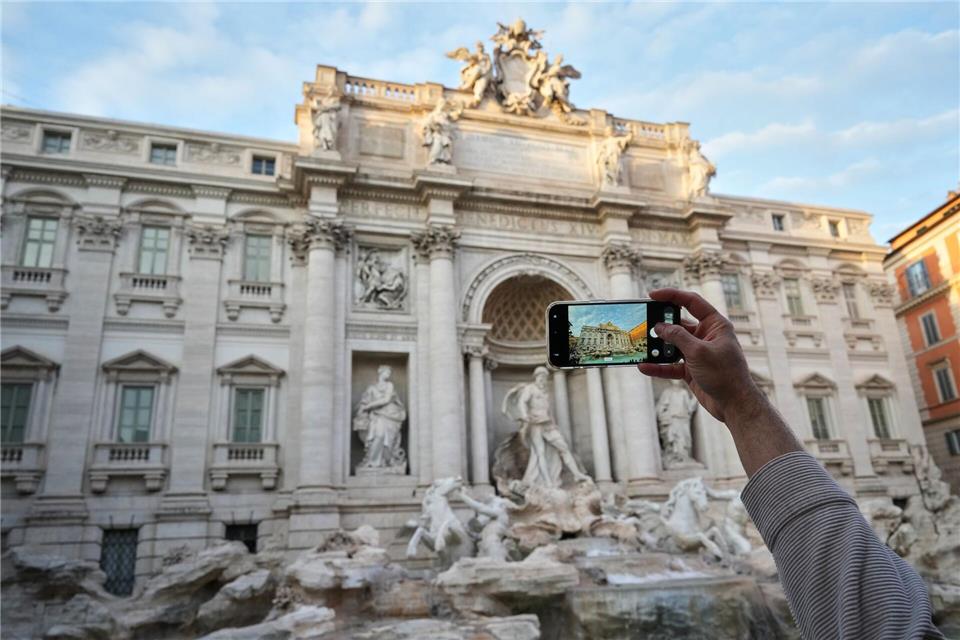 Ein Besucher macht ein Foto des Trevi-Brunnens. (Archivbild)Andrew Medichini/AP/dpa