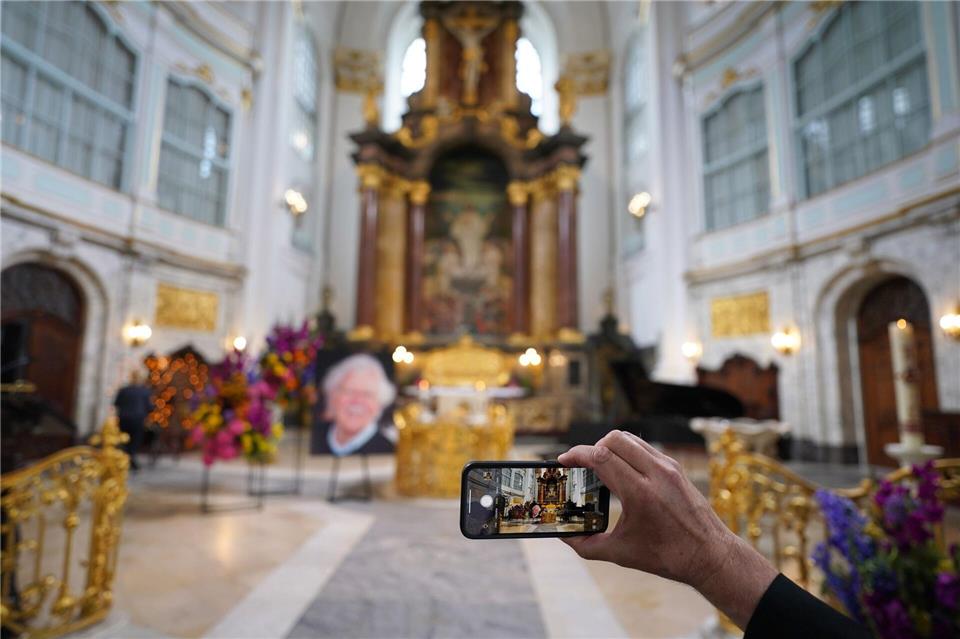 Ein Besucher macht zu Beginn der Trauerfeier ein Foto mit einem Smartphone.Marcus Brandt/dpa