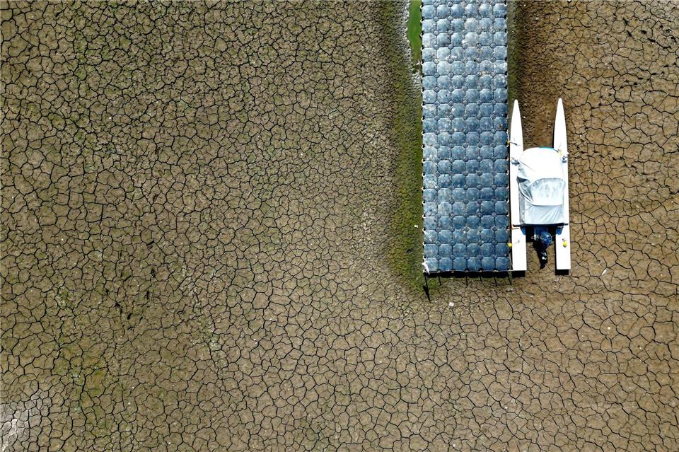 Ein Boot liegt in einem wegen des niedrigen Wasserstands im Rhein trocken gefallenen Hafenbecken.Federico Gambarini/dpa
