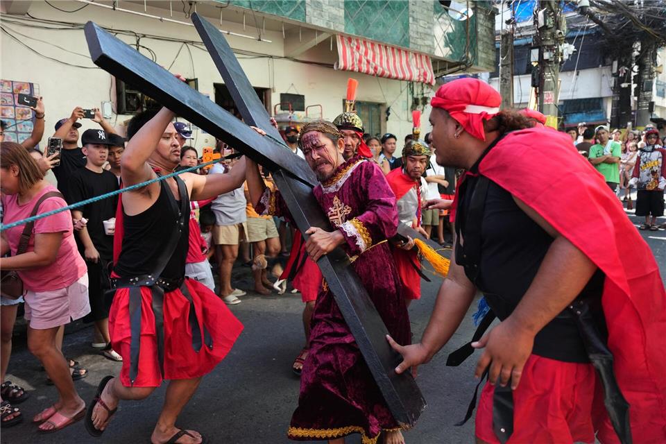 Ein Büßer mit einem Holzkreuz während eines Passionsspiels in Mandaluyong, das die Leiden Jesu Christi nachstellt. Die Szene spielt am Gründonnerstag im Rahmen der Karwochen-Feierlichkeiten.Aaron Favila/AP/dpa