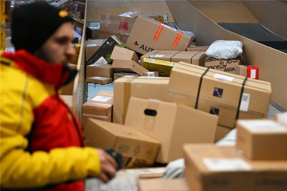 Ein DHL-Paketbote ist in einer Zustellbasis mit einer Vielzahl an Paketen beschäftigt. Der Logistikkonzern hat Jahreszahlen für 2025 vorgelegt, er hat profitablere Geschäfte gemacht als zuvor.Wolf von Dewitz/dpa
