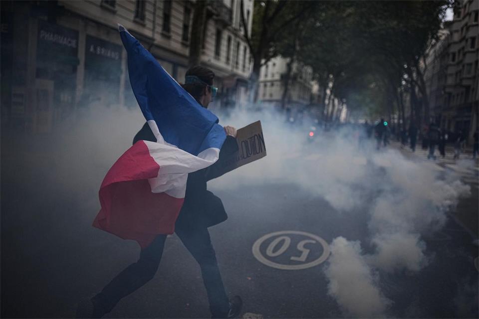 Ein Demonstrant hält während einer Demonstration in Lyon gegen steigende Lebenshaltungskosten eine französische Flagge.Laurent Cipriani/AP/dpa