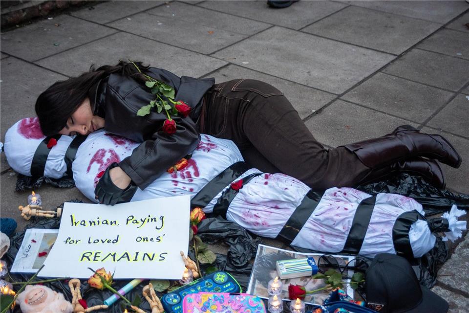 Ein Demonstrant liegt mit einem menschlichen Leichnam, der ein Opfer symbolisiert, auf dem Boden.Krisztian Elek/SOPA Images via ZUMA Press Wire/dpa