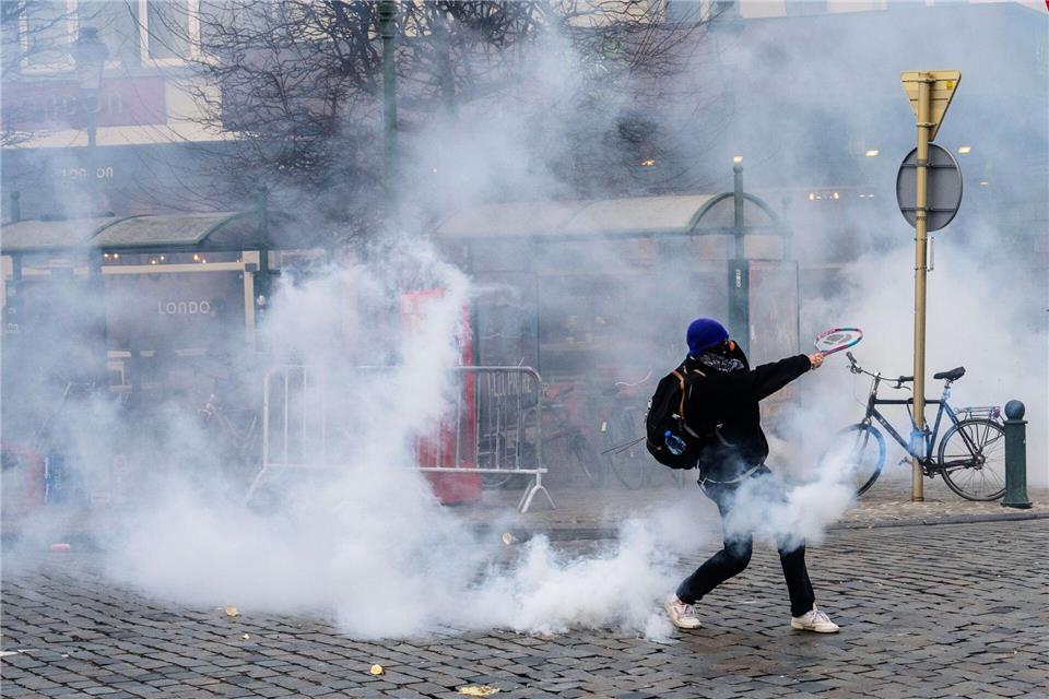 Ein Demonstrant schlägt bei den Protesten in Brüssel gegen einen Tränengasbehälter.  Marius Burgelman/AP/dpa