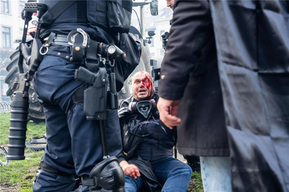 Ein Demonstrant sitzt verletzt auf einem Bordstein. Marius Burgelman/AP/dpa
