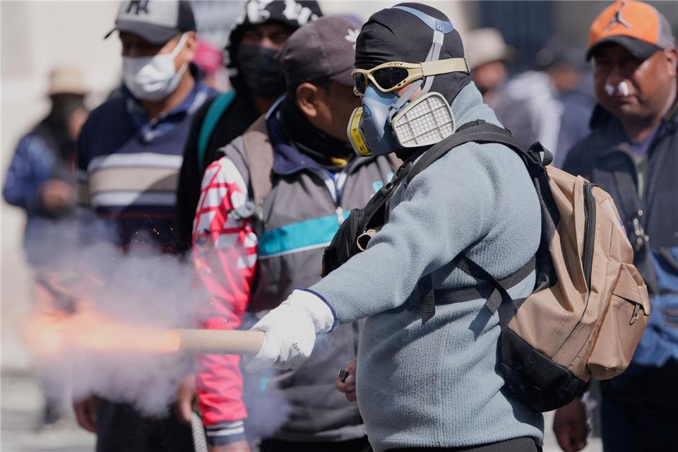 Ein Demonstrant wirft einen Feuerwerkskörper auf die Polizei.Juan Karita/AP/dpa