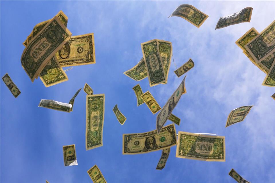 Ein-Dollar-Scheine aus den USA fallen mit dem Himmel im Hintegrund in Dallas.LM Otero/AP/dpa