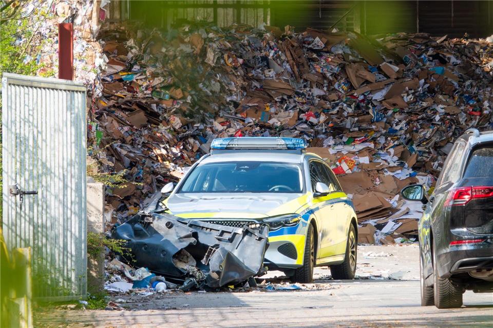 Ein Einsatzwagen der Polizei steht auf dem Gelände einer Recyclingfirma, wo ein toter Mann gefunden wurde. Bodo Marks/dpa
