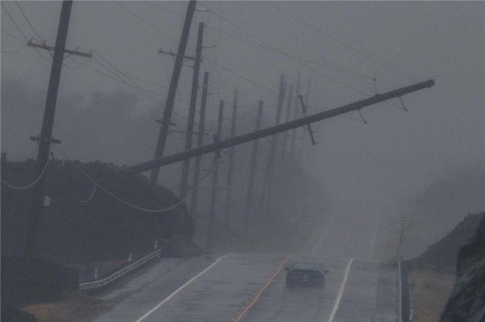 Ein Fahrzeug fährt in der Nähe von Ocean View auf Hawaii während des Hurrikans „Lala“ an einem umgestürzten Strommast vorbei, der über dem Mamalahoa Highway hängt.Stephen Lam/San Francisco Chronicle/AP/dpa