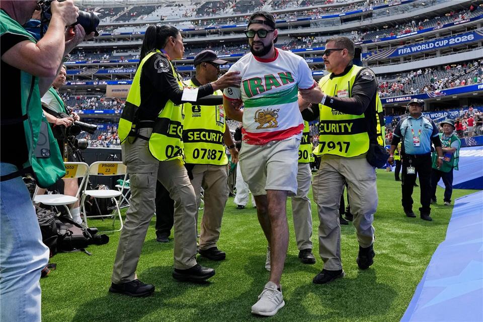 Ein Fan mit der von der FIFA verbotenen älteren Iran-Symbolik wird abgeführt. Gregory Bull/AP/dpa