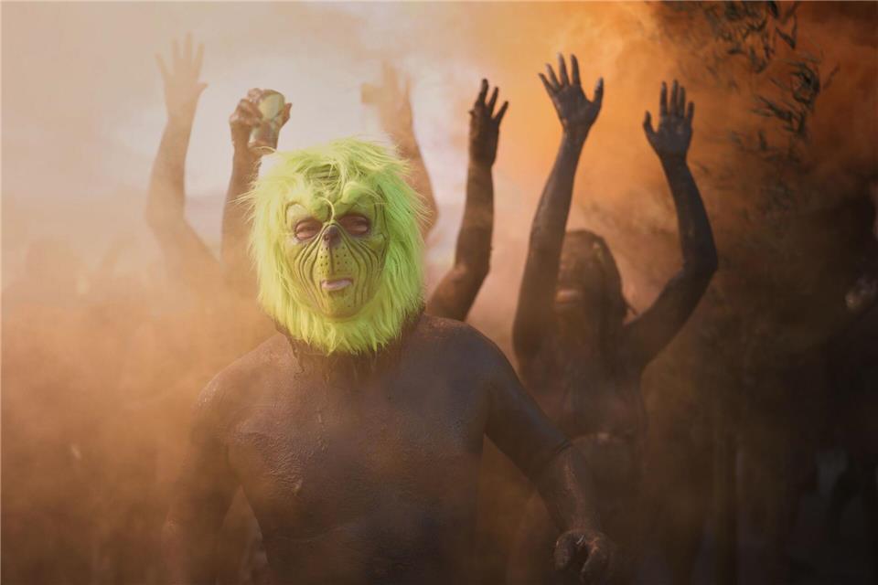 Ein Feiernder mit einer Grinch-Maske posiert während der Mud Block Karnevalsparty in Brasilien.Andre Penner/AP/dpa