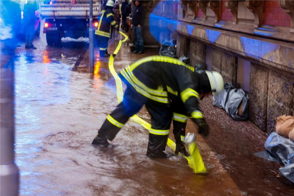 Ein Feuerwehr-Mitarbeiter verlegt einen Schlauch, um Hochwasser in Flensburg abzupumpen. (Archivbild)Frank Molter/dpa