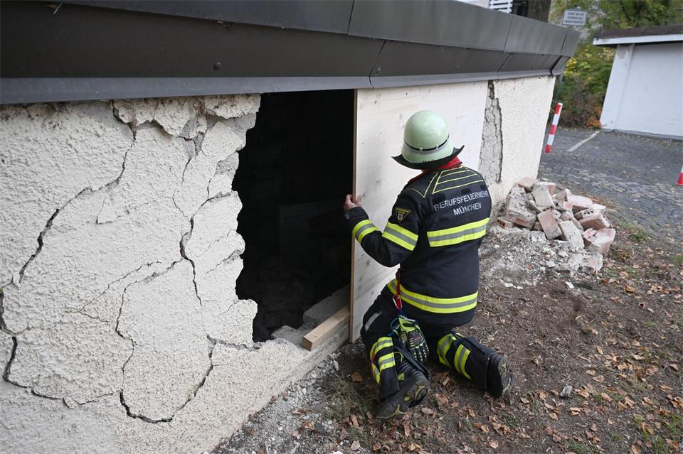 Ein Feuerwehrmann deckt das Loch in der Garagenwand ab. Felix Hörhager/dpa