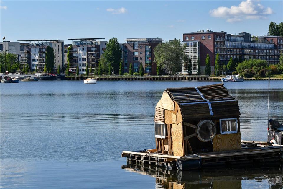Ein Floß mit einem zusammengezimmerten Holzhaus schwimmt auf dem Rummelsburger See. (Archivbild) Jens Kalaene/dpa-Zentralbild/ZB