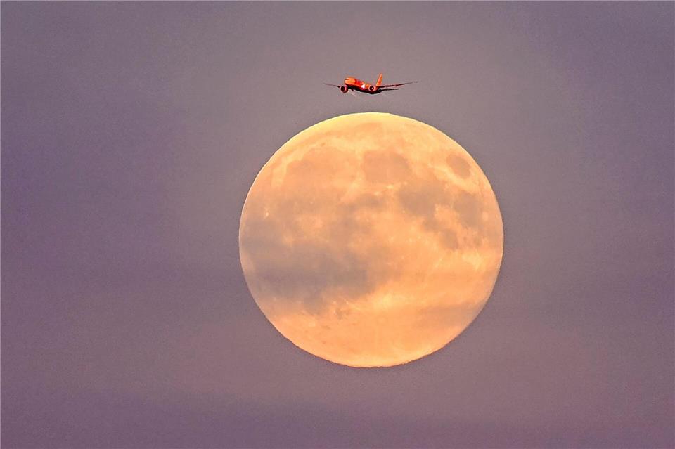 Ein Flugzeug fliegt vor dem sogenannten Supermond am frühen Abend über Leipzig.Jennifer Brückner/dpa