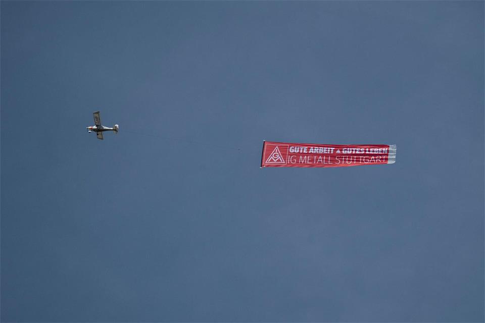 Ein Flugzeug mit einem IG-Metall-Banner fliegt über das Porsche-Stammwerk in Zuffenhausen.Marijan Murat/dpa
