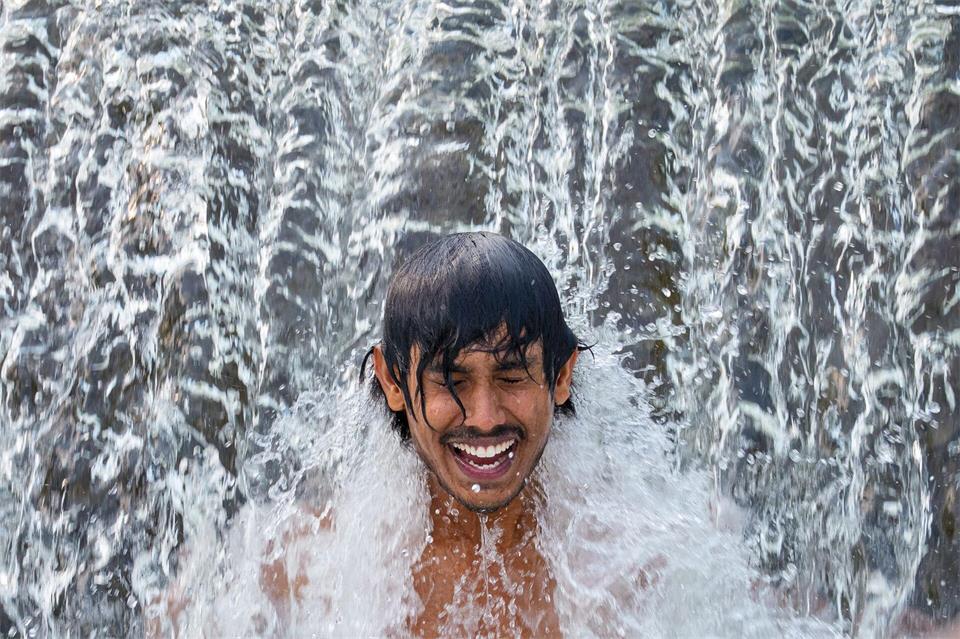 Ein Gastarbeiter aus Sri Lanka kühlt sich an einem glühend heißen Tag in einer Wasserkaskade eines Flusses außerhalb der Stadt Bragadiru in Rumänien ab.Andreea Alexandru/AP/dpa