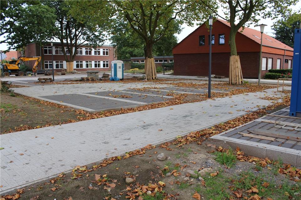 Ein Großteil der Parkplätze ist fertig gepflastert. Auch am Schulhof (kleines Bild) wird gearbeitet.