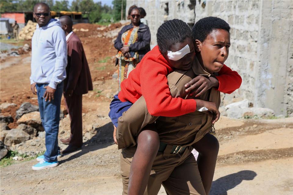 Ein Helfer trägt eine verletzte Schülerin.Andrew Kasuku/AP/dpa