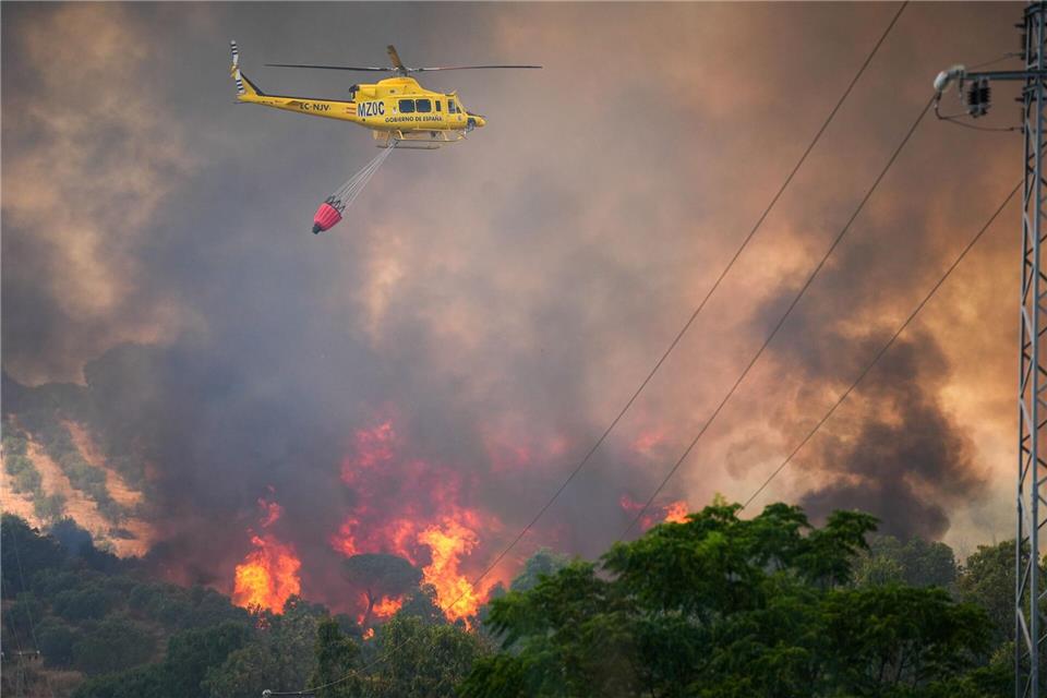 Ein Hubschrauber ist bei einem Waldbrand in Spanien am Odiel-Fluss in der Gemeinde Gibraleón im Einsatz.María José López/Europa Press/dpa
