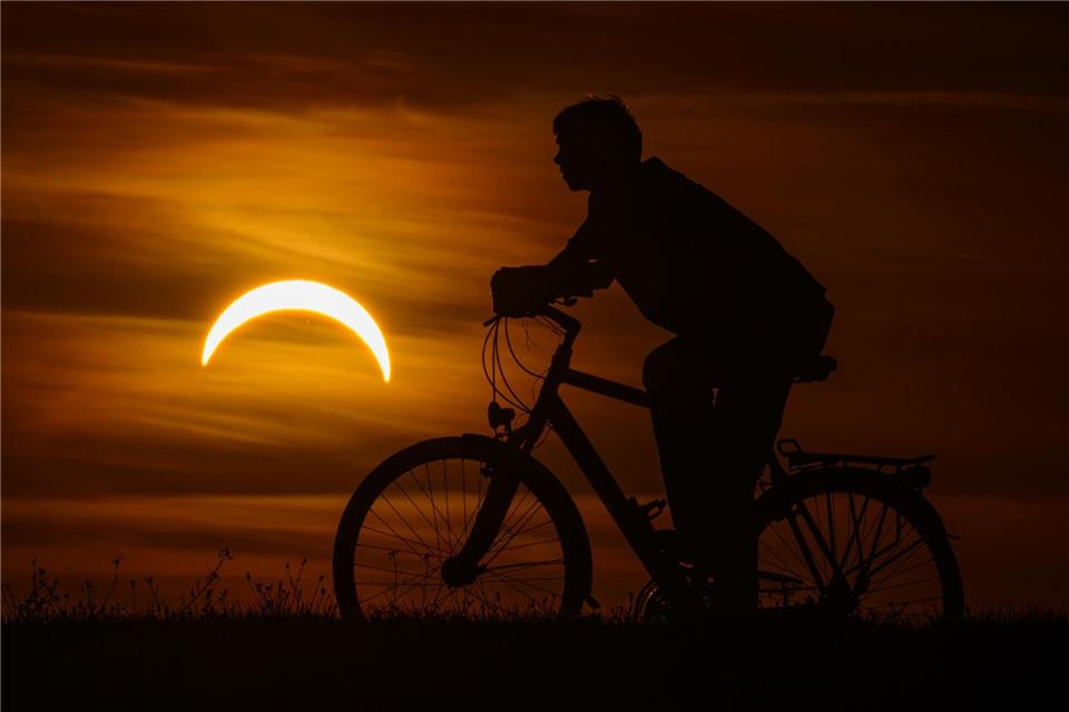 Ein Junge auf einem Fahrrad betrachtet die partielle Sonnenfinsternis in Jacobsdorf, im östlichen Brandenburg.Patrick Pleul/dpa