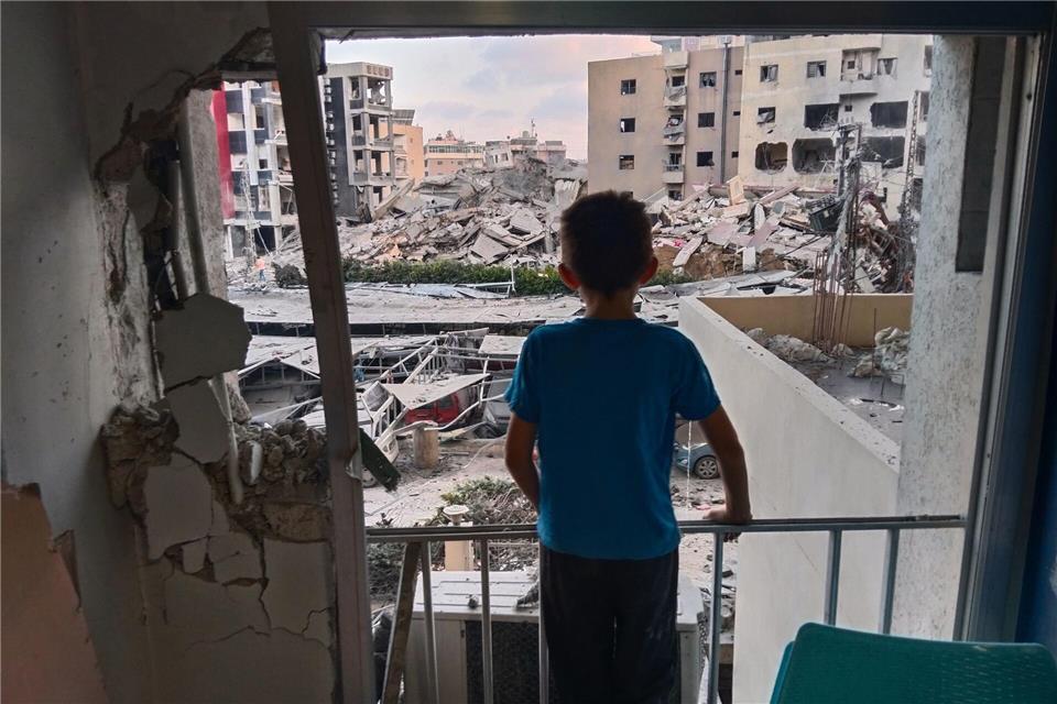 Ein Junge blickt aus einem beschädigten Raum des Jabal Amel Krankenhauses auf ein zerstörtes Gebäude, das bei einem israelischen Luftangriff in der südlichen Hafenstadt Tyrus getroffen wurde.Uncredited/AP/dpa