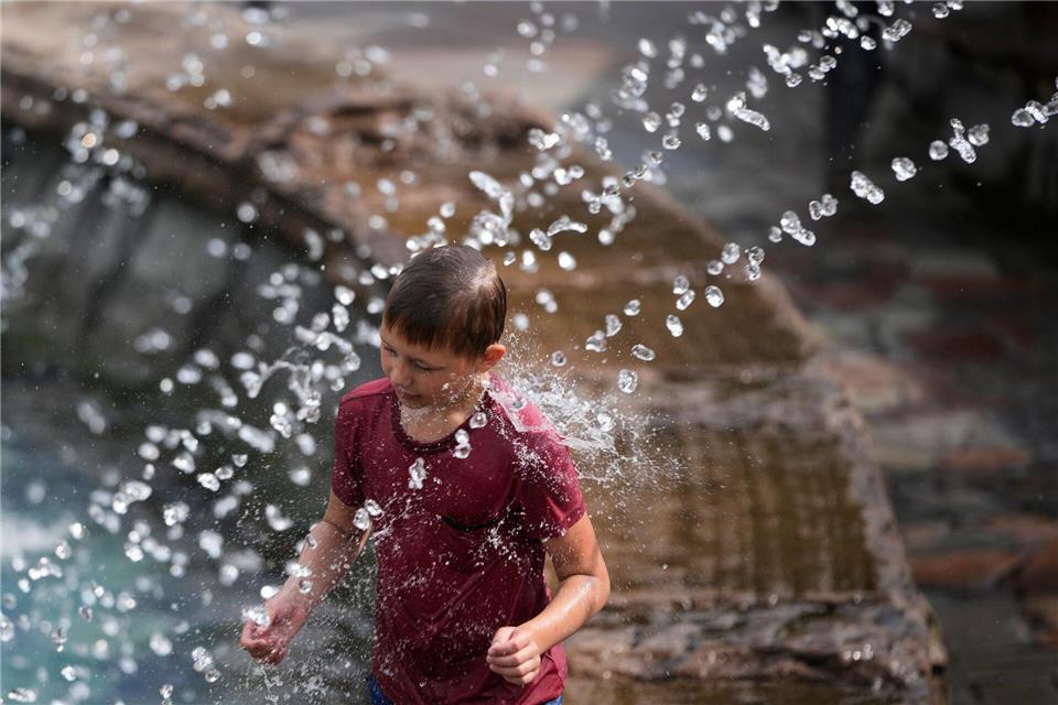 Ein Junge kühlt sich an einem heißen Sommertag in einem Springbrunnen in Moskau ab.Pavel Bednyakov/AP/dpa