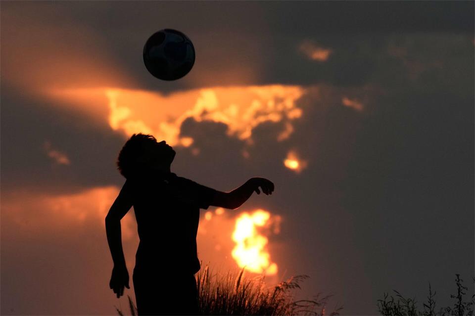 Ein Junge spielt Fußball, während die Sonne über der Mittelmeerküste in Beirut untergeht.Bilal Hussein/AP/dpa