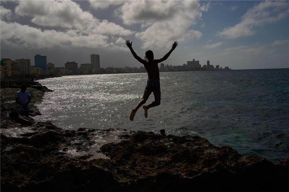 Ein Junge springt ins Meer, auch wenn der Strom in Land ausgefallen ist.Ramon Espinosa/AP/dpa
