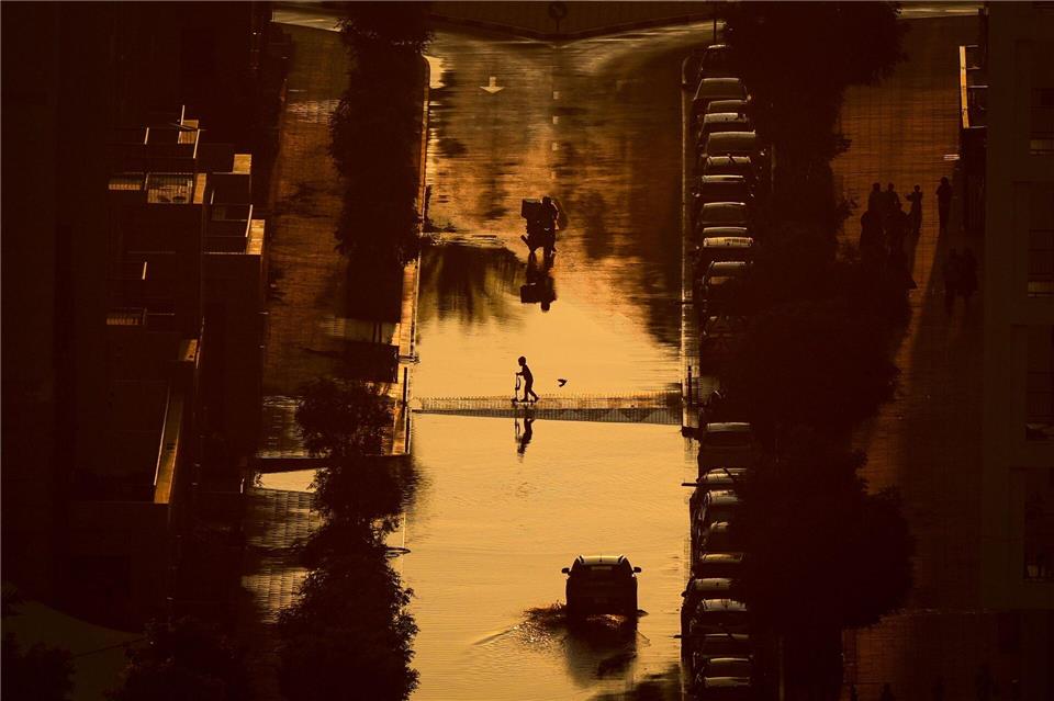 Ein Junge überquert eine mit Regenwasser gefüllte Straße in Schardscha, Vereinigte Arabische Emirate.Uncredited/AP/dpa