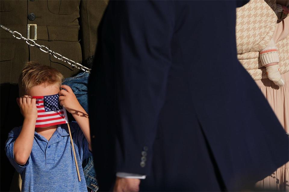 Ein Junge verdeckt sein Gesicht mit einer amerikanischen Flagge.Julia Demaree Nikhinson/AP/dpa