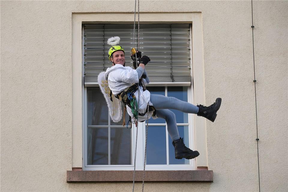 Ein Kamerad der Höhenrettung der Chemnitzer Feuerwehr seilt sich im Weihnachtsengel-Kostüm an der Fassade des Klinikums Chemnitz ab.Sebastian Willnow/dpa