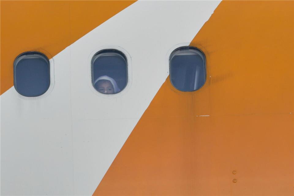 Ein Kind blickt aus einem von Venezuela betriebenen Flugzeug, das mit abgeschobenen Migranten aus den USA auf dem Flughafen Simon Bolivar International in Maiquetia ankommt.Cristian Hernandez/AP/dpa