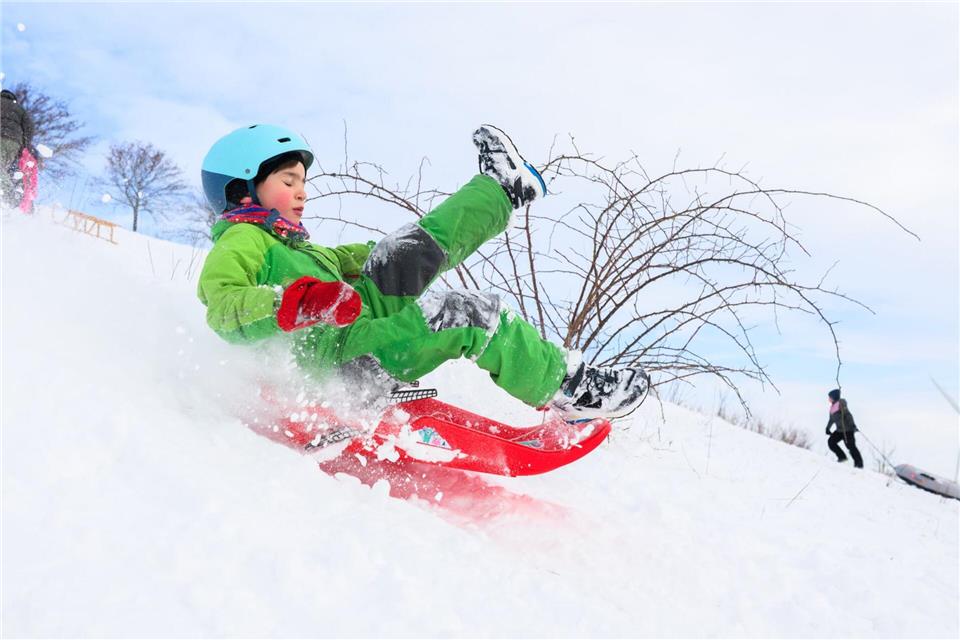 Ein Kind fährt mit seinem Schlitten am Kronsberg.Julian Stratenschulte/dpa