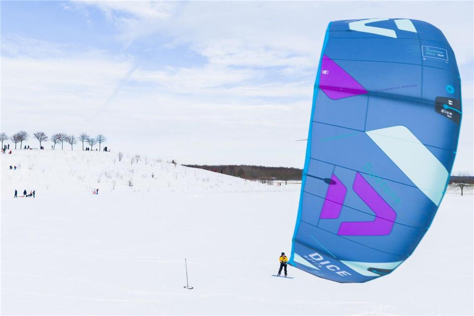Ein Kite-Surfer gleitet am Kronsberg mit seinem Board über den Schnee.Julian Stratenschulte/dpa