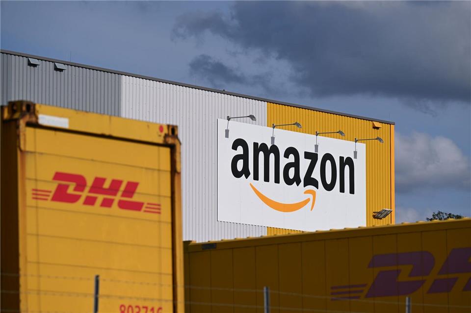 Ein Logistikzentrum von Amazon, auf dessen Gelände DHL-Container stehen. DHL ist das größte Paketunternehmen in Deutschland, gefolgt von Amazon - der Online-Handelsriese trägt einen großen Teil bei ihm bestellten Waren selbst aus. (Archivbild)Wolf von Dewitz/dpa