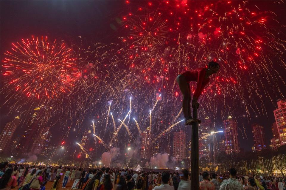 Bilder des Tages Ein Mädchen performt auf einer Mallakhamb-Stange, während Feuerwerkskörper den Himmel während des Diwali-Lichterfestes in Mumbai erhellen.Rafiq Maqbool/AP/dpa
