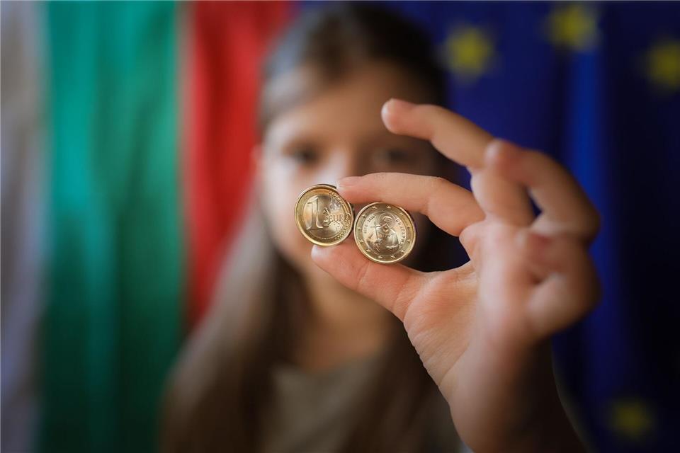Ein Mädchen zeigt neue Euro-Münzen mit bulgarischen Symbolen.Valentina Petrova/AP/dpa