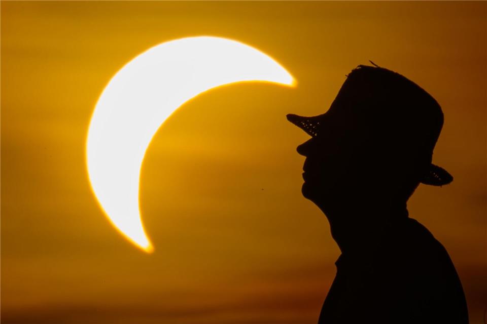 Ein Mann betrachtet die partielle Sonnenfinsternis im östlichen Brandenburg.Patrick Pleul/dpa
