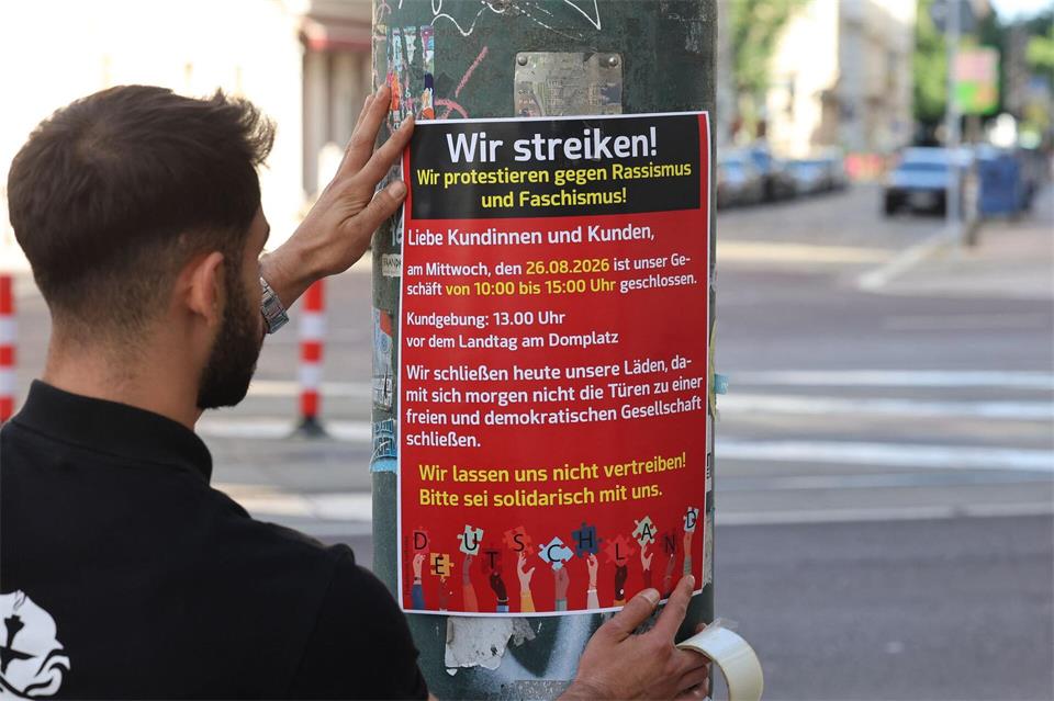 Ein Mann bringt ein Plakat zum Streikaufruf an.Peter Gercke/dpa